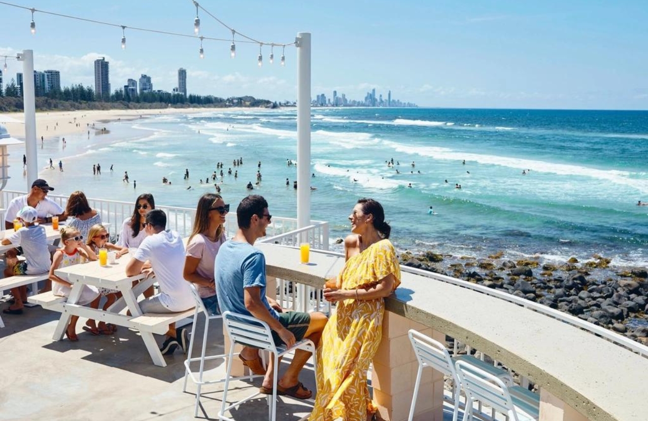 Burleigh Heads from a beachfront bar, juice on the tables and the Gold Coast skyline beyond the surf.