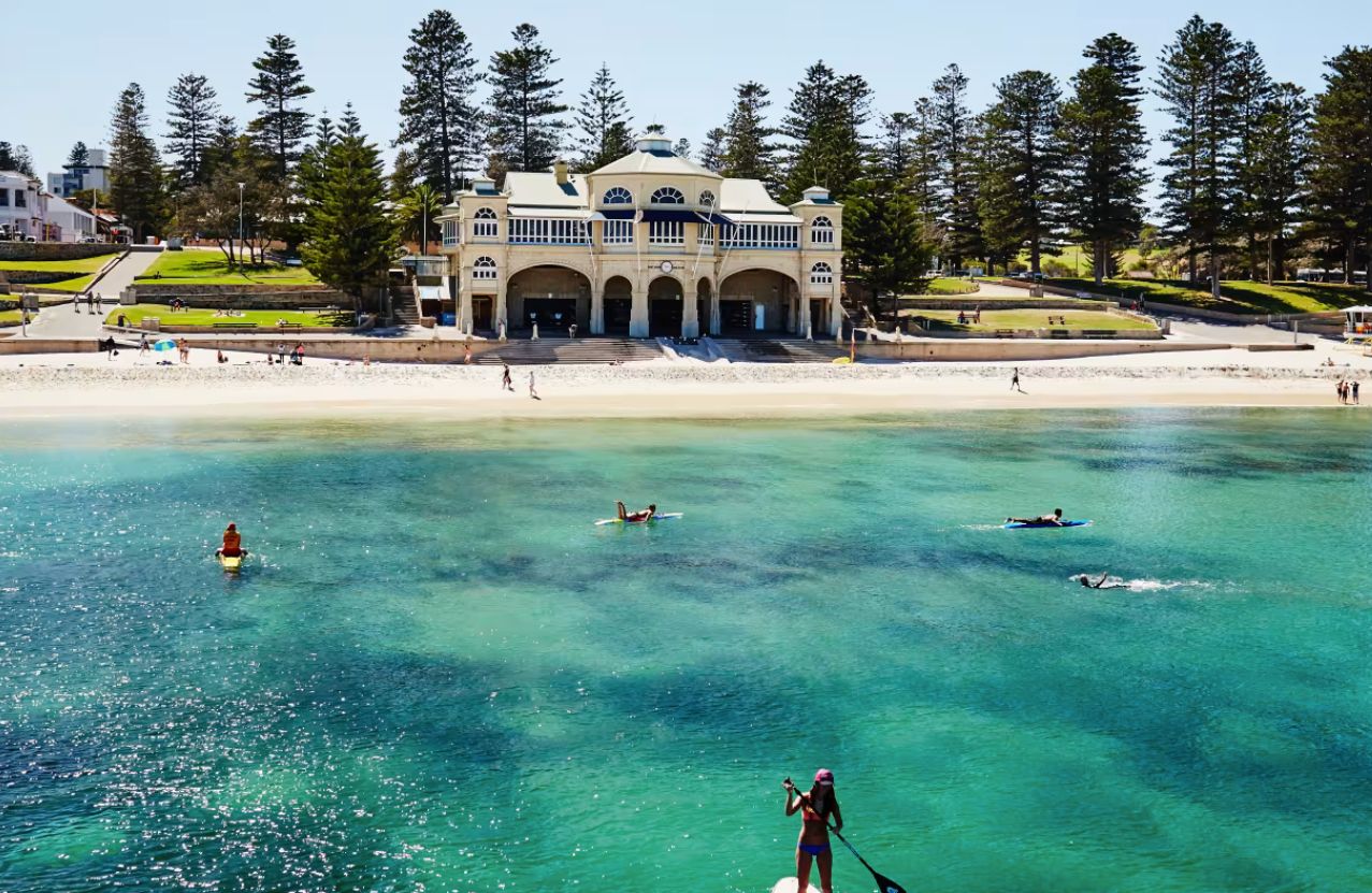 Cottesloe Beach, the Indiana Tea House, and people on boards in clear green water.
