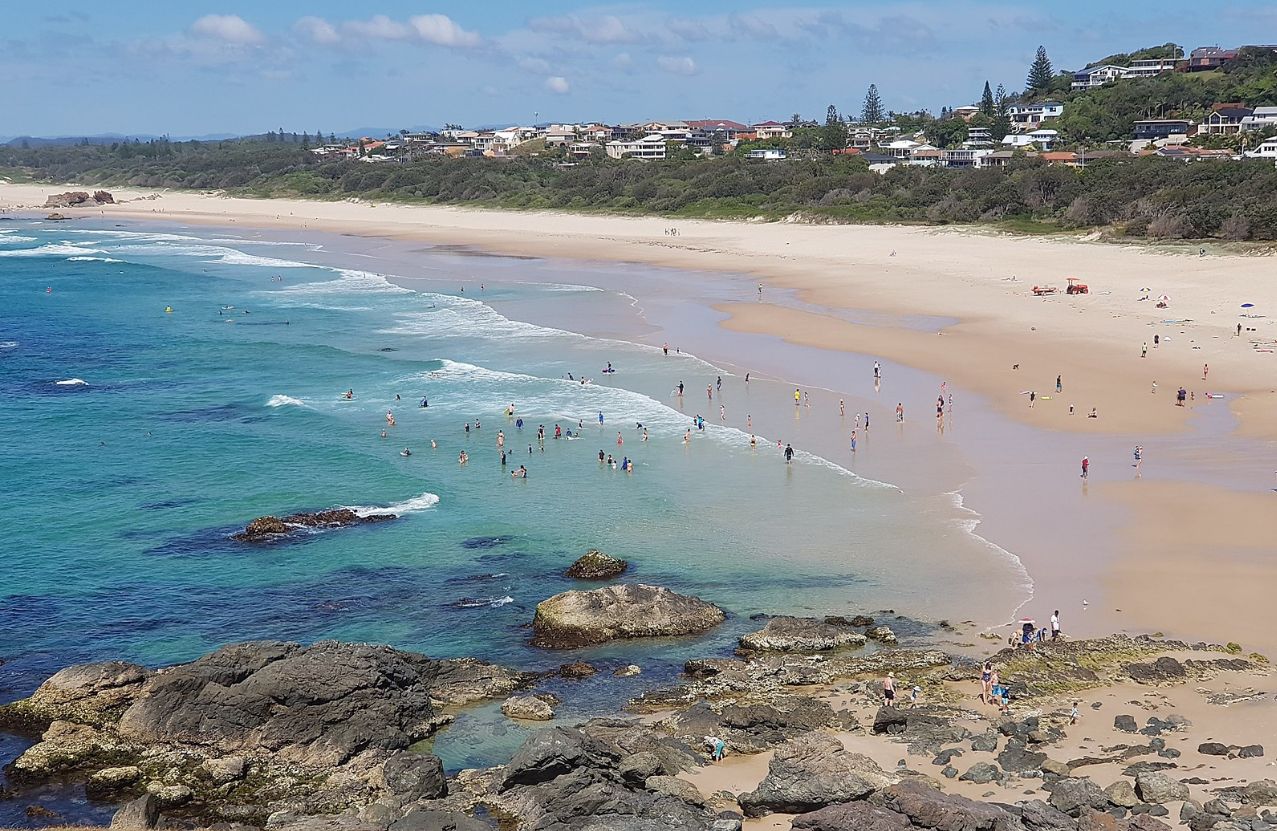 Lighthouse Beach at Port Macquarie, swimmers in clear water and houses along the dune.