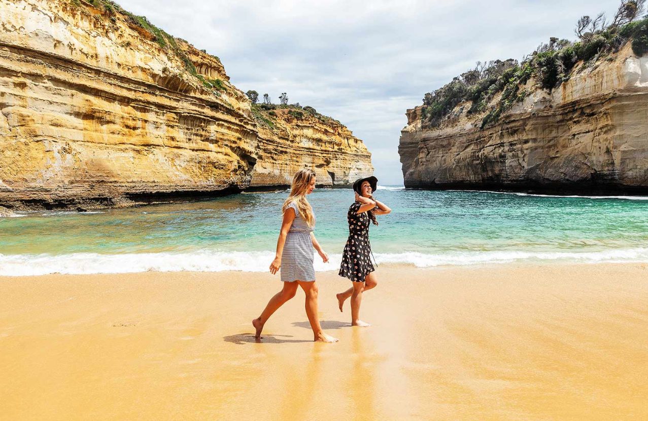 Loch Ard Gorge, two walkers on the sand between the limestone walls.