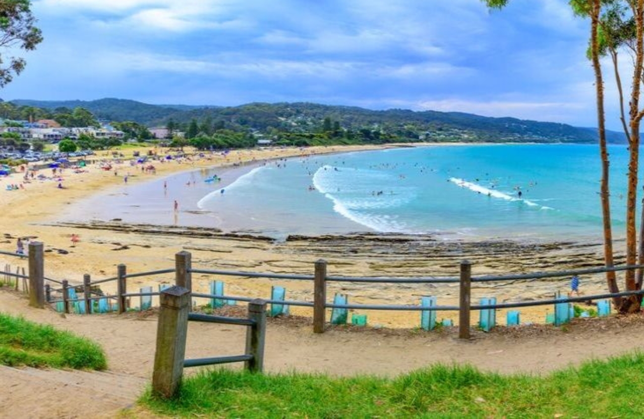 Lorne Main Beach from the foreshore steps, swimmers inside the curve of the bay.