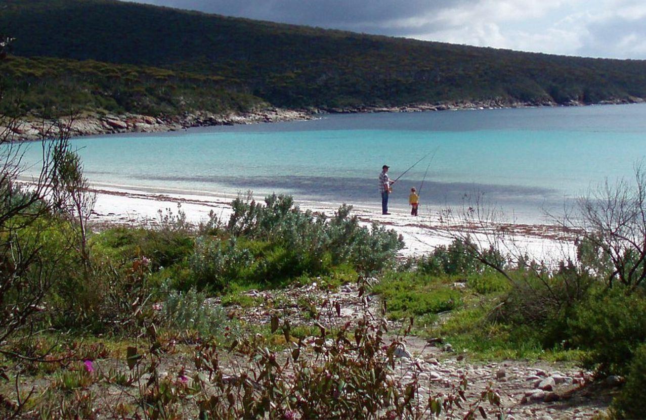 Memory Cove, a father and child fishing the shallows of a lonely turquoise bay.