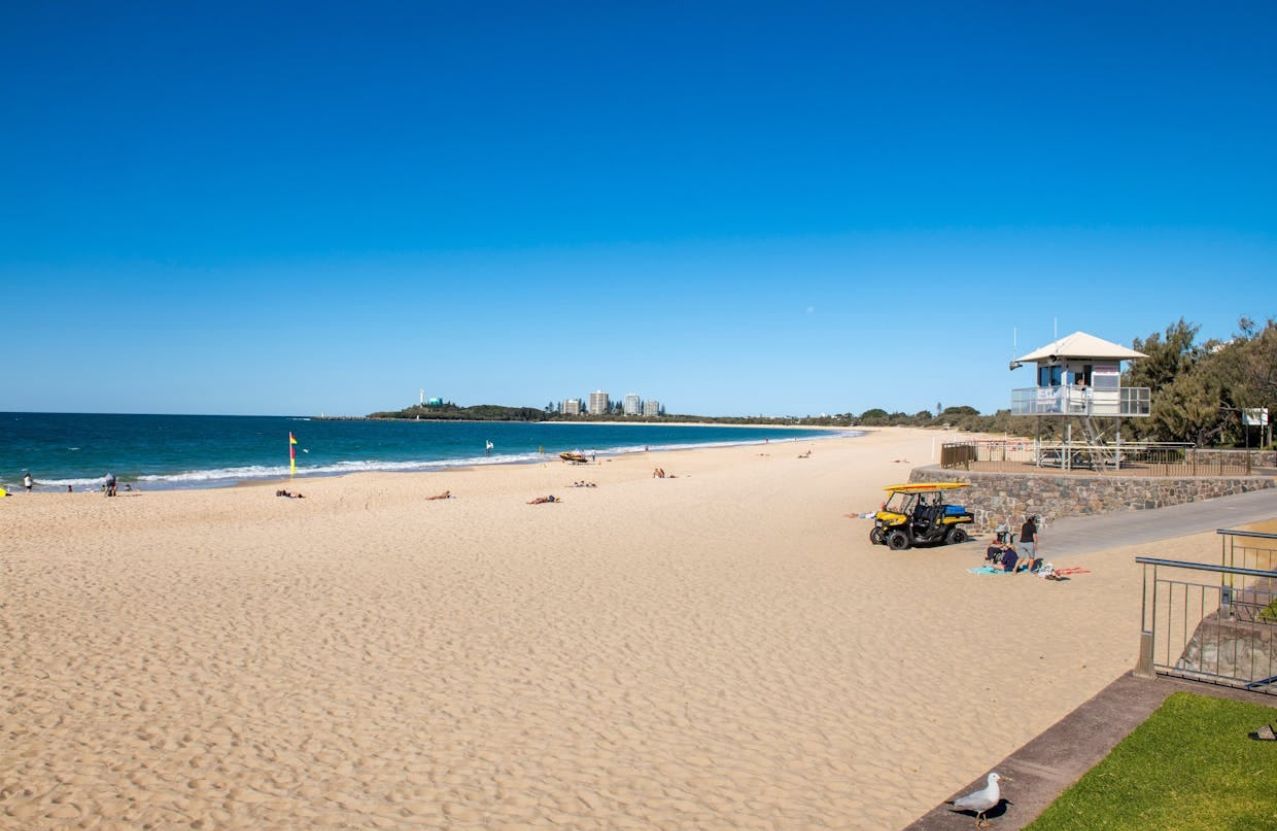 Mooloolaba Main Beach, a wide empty stretch of sand, the surf tower, and a lifeguard buggy.