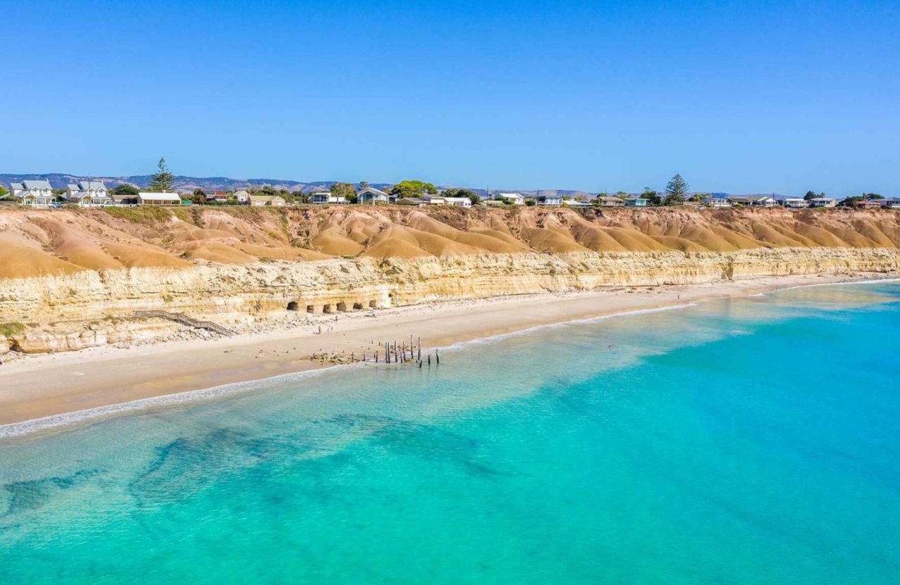 Port Willunga, ochre cliffs, the old jetty piles, and clear turquoise water.